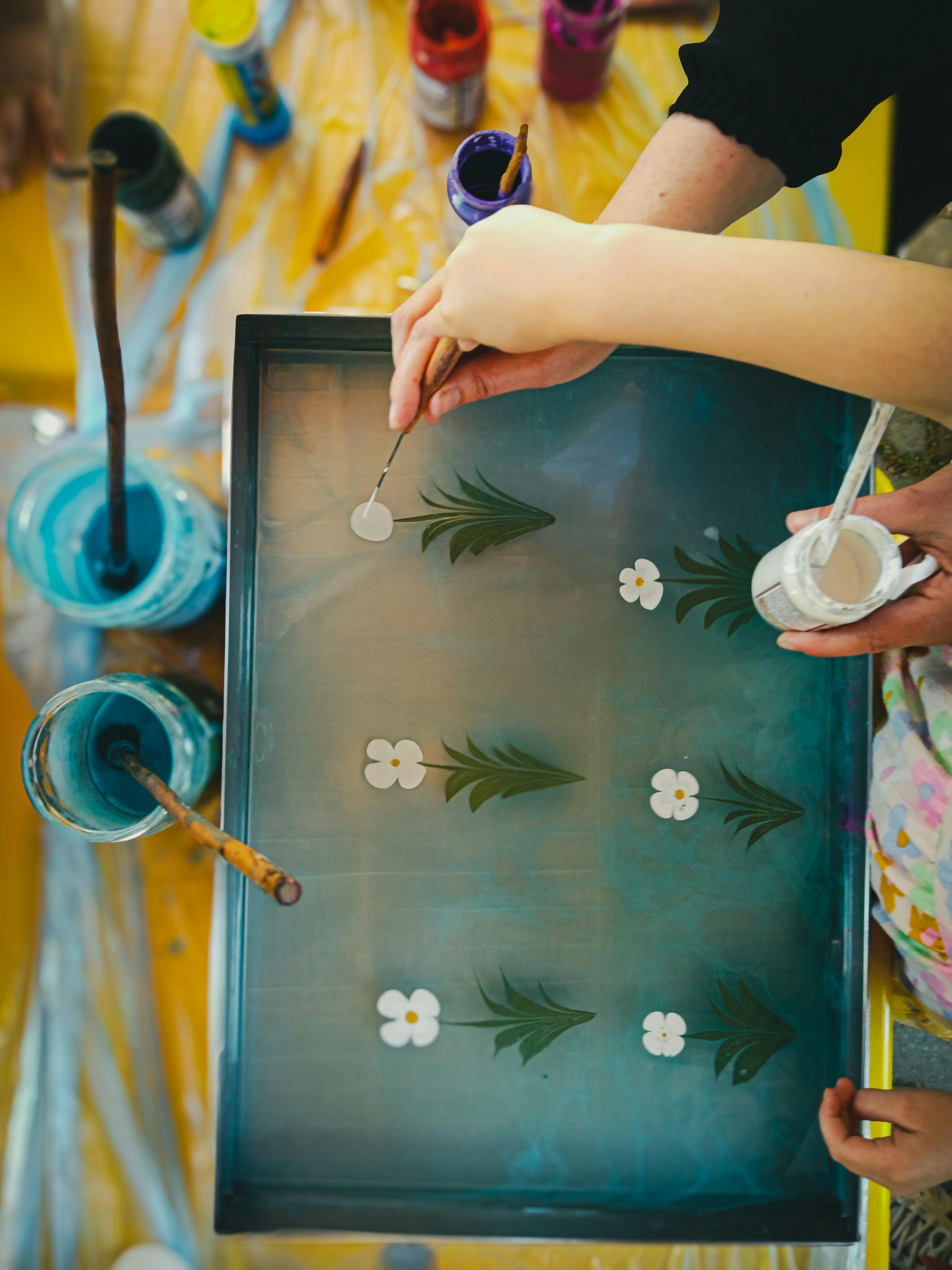 Close-up of children's hands creating beautiful Ebru art with colorful paints.