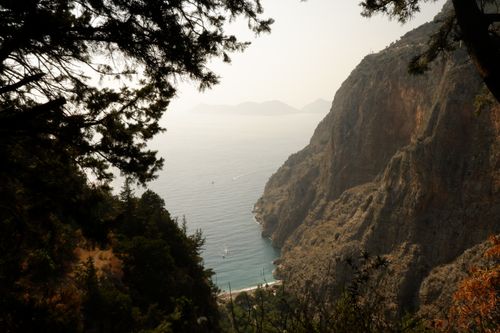 Free A breathtaking coastal landscape featuring towering cliffs and a serene sea view, framed by lush trees. Stock Photo