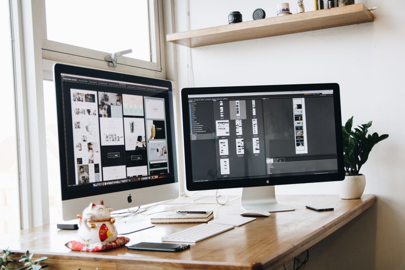 Espace de travail avec double écran montrant des maquettes de design