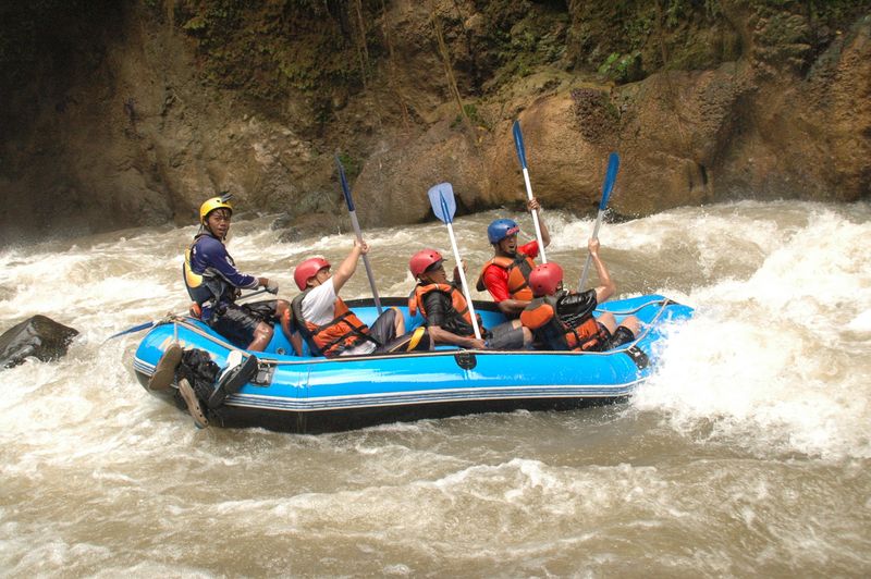 Balsa de rafting en rápidos de clase IV con cinco personas con cascos y chalecos naranjas