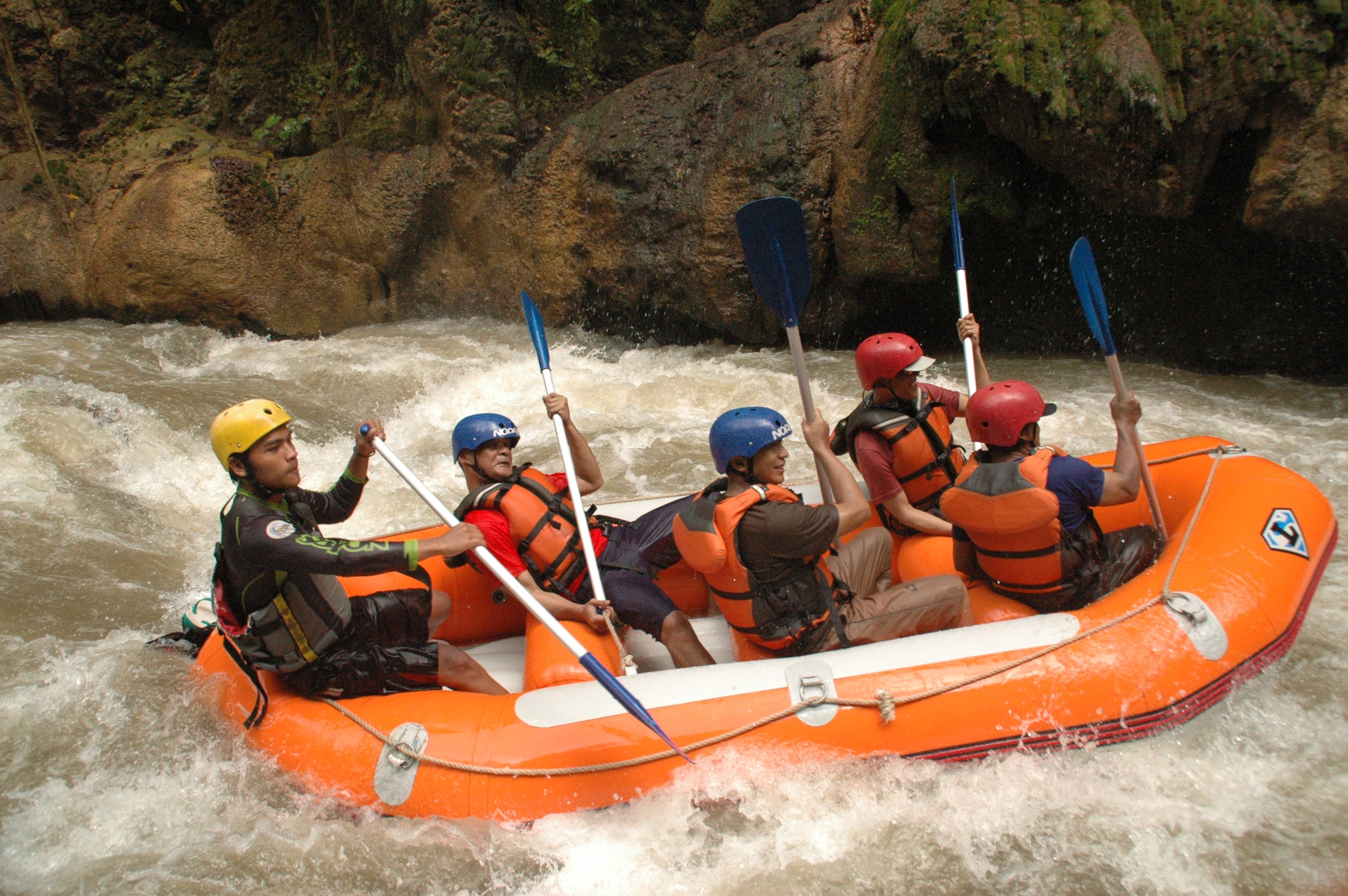 Group of people whitewater rafting in a canyon, experiencing thrilling rapids.