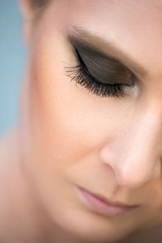 Artistic close-up of a woman with elegant smokey eye makeup and long lashes.