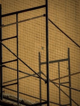 Creative capture of scaffold shadows on a wall, highlighting geometric patterns.