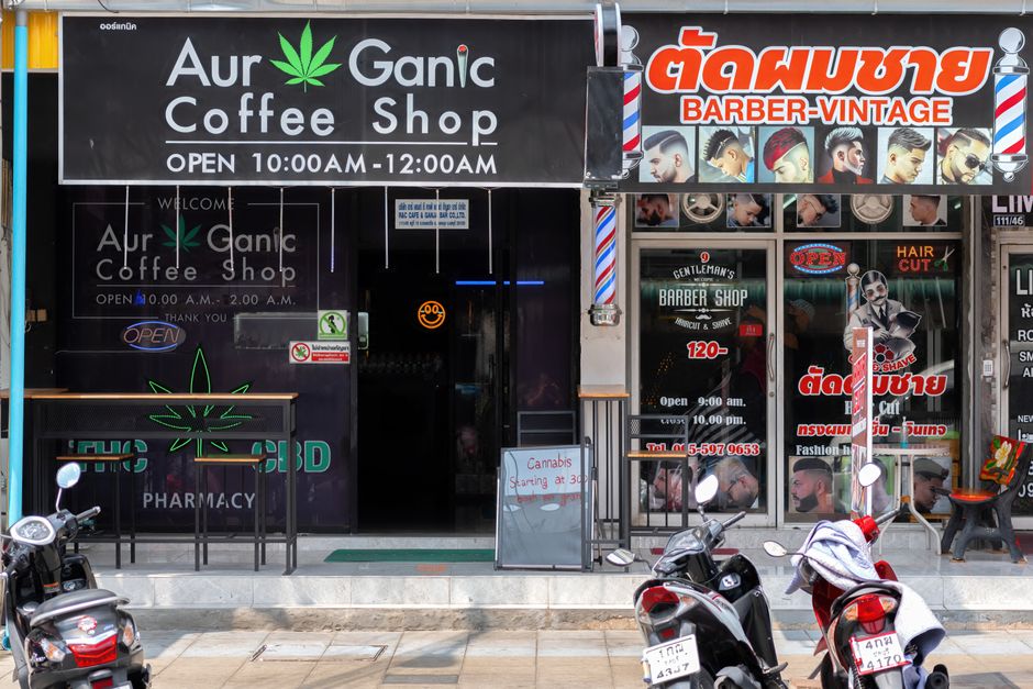 Street view showing 'Aur Ganic Coffee Shop' and a barber shop in Pattaya, Thailand.