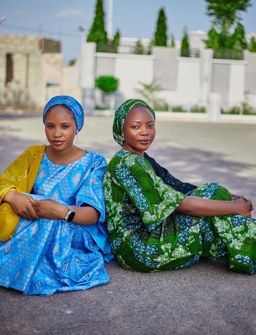Free Two women sitting outdoors in colorful traditional African dresses, radiating elegance and cultural pride. Stock Photo