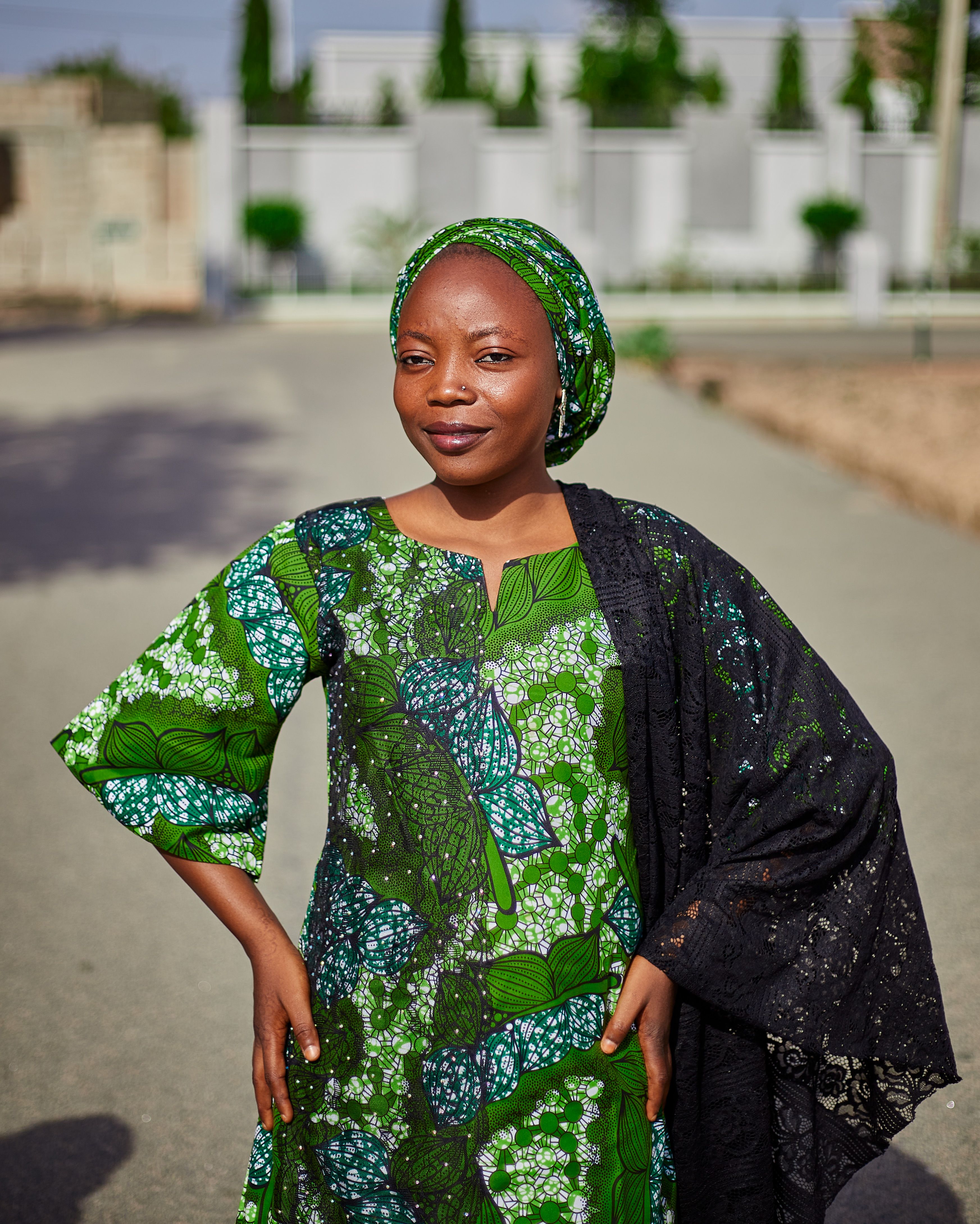 Confident woman in vibrant green dress standing outdoors, exuding grace and poise.