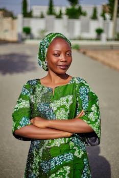A woman stands confidently outdoors in a vibrant green African patterned dress, radiating elegance.
