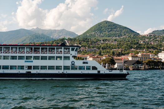 A picturesque ferry on Lake Como with a stunning mountain backdrop under a clear summer sky.