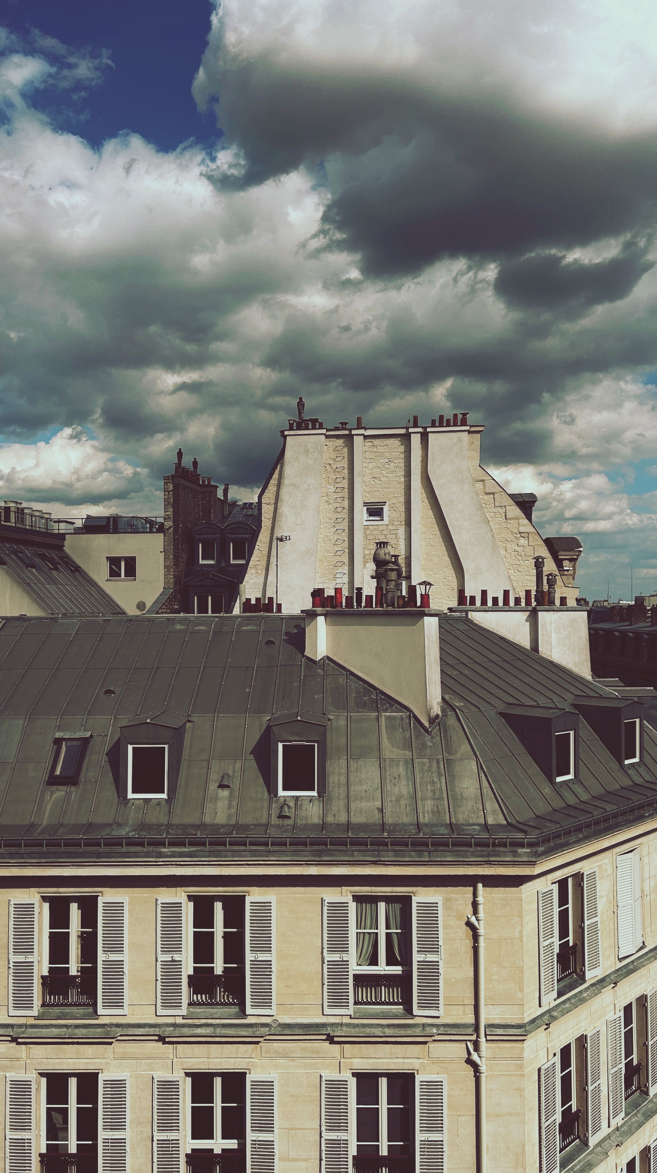 A scenic view of Parisian rooftops under a dramatic cloudy sky, capturing the essence of urban Paris.
