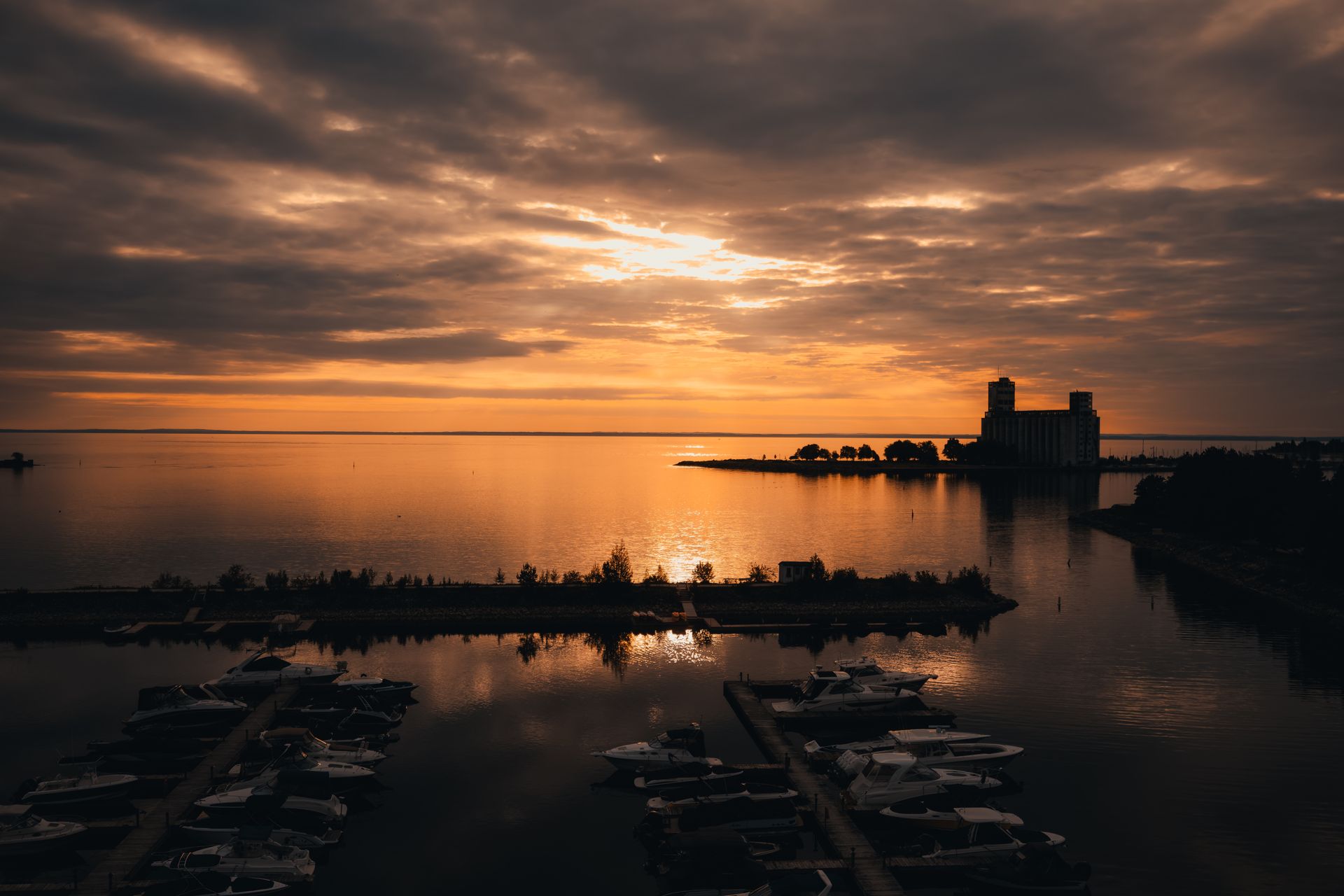 Stunning sunrise view over Collingwood Harbor with boats and reflections on the water.