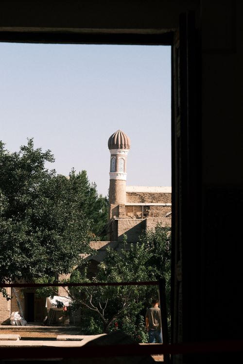 Free A picturesque view of a traditional minaret framed by an open doorway, surrounded by greenery. Stock Photo