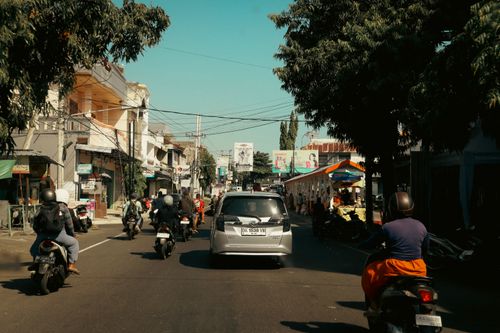 Free Busy urban road in Bali, Indonesia with motorcycles and cars under a sunny sky. Stock Photo