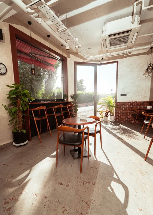 Free Sunlit modern cafe interior in Baghdad with wooden furniture, plants, and a cozy atmosphere. Stock Photo