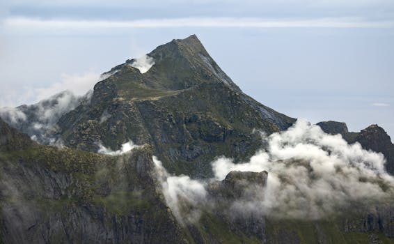 Stunning view of Lofoten's rugged mountain peaks shrouded in clouds, showcasing Norway's natural beauty.