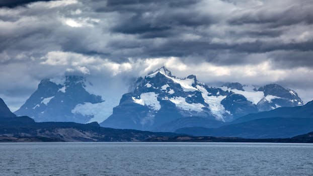 Stunning view of snow-capped mountains under dramatic clouds in Patagonia, perfect for nature and travel themes.
