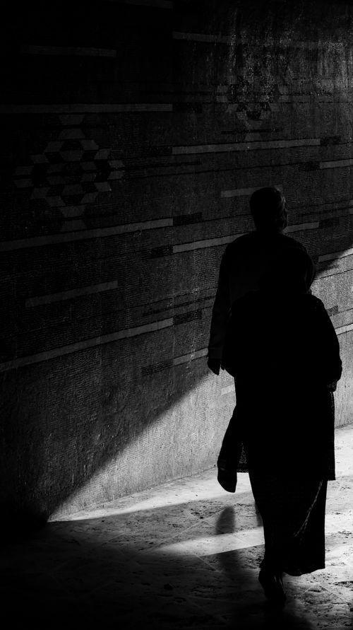 Free Artistic black and white silhouette of two people walking in a shadowy corridor. Stock Photo