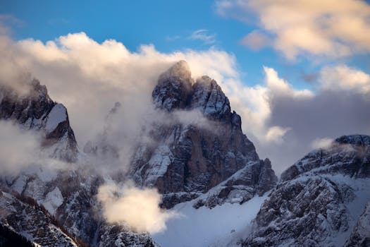 Breathtaking view of snow-covered Dolomite peaks with vibrant clouds during sunset in Italy.