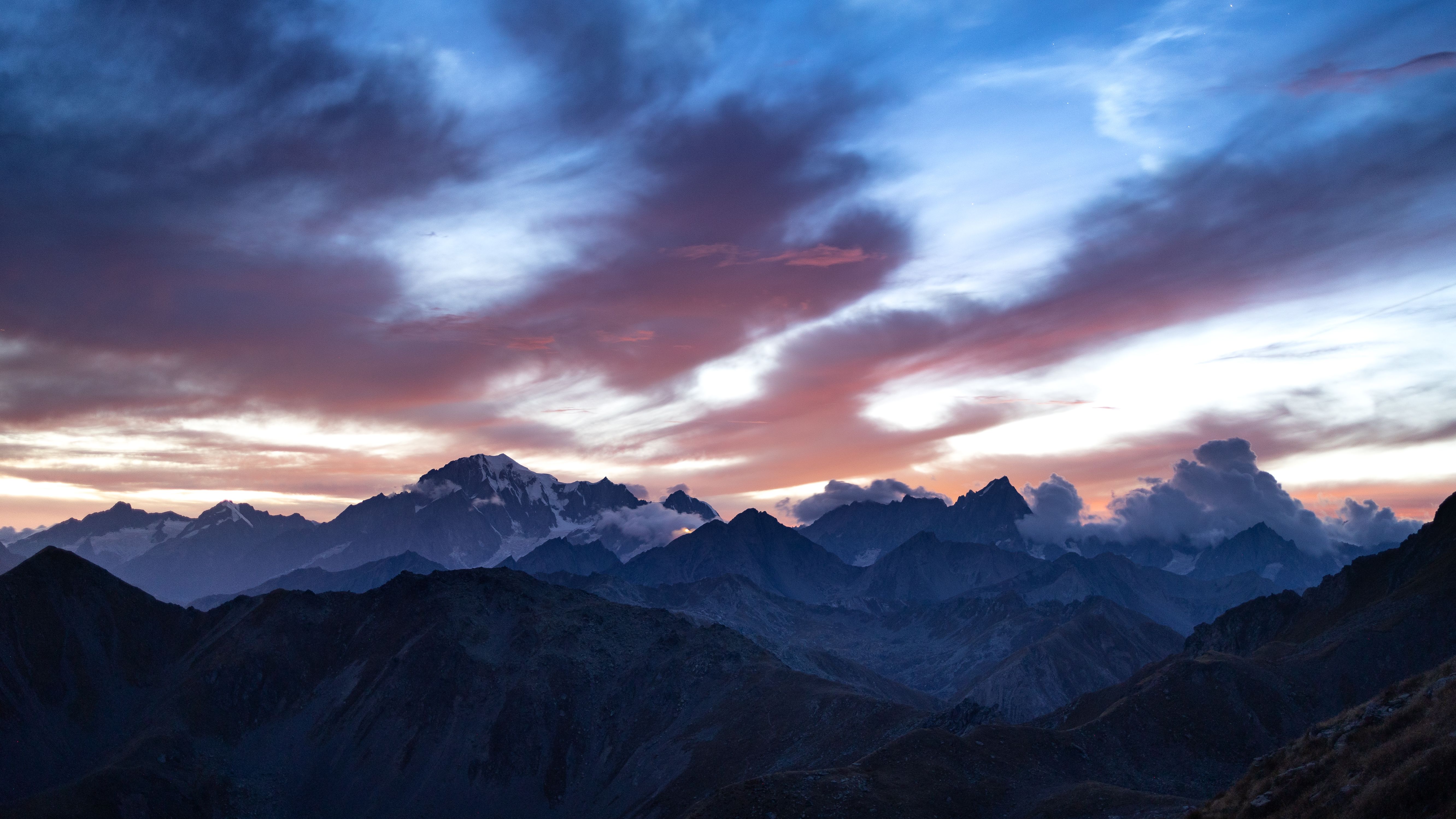 Dramatic panoramic mountain summit vista with layered peaks at sunset