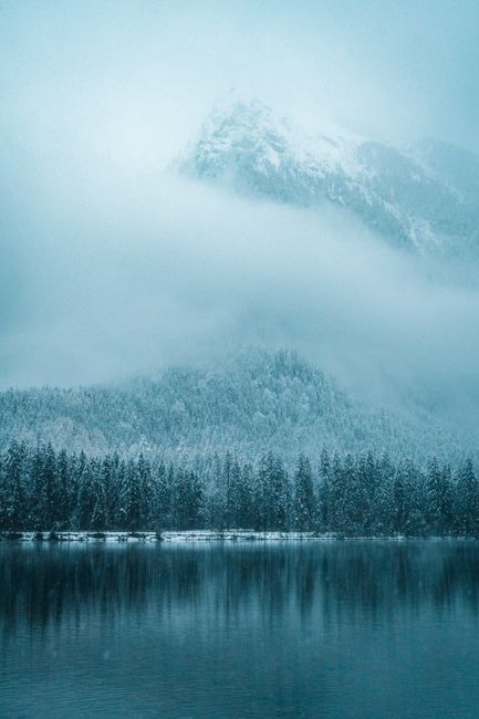 A tranquil winter scene of snow-covered mountains and a reflective lake in Ramsau, Germany.