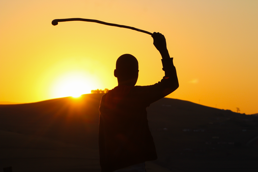 Silhouette of a person with stick against a vivid sunset in Harding, KwaZulu-Natal, South Africa.