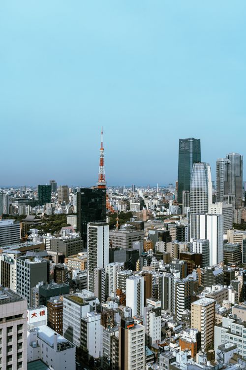 Free Aerial view of Tokyo's urban landscape showcasing Tokyo Tower and skyscrapers against a clear blue sky. Stock Photo