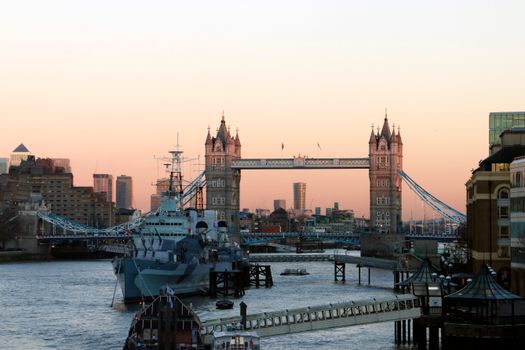 Sunset over Tower Bridge and HMS Belfast on the Thames in London, capturing a serene urban landscape.