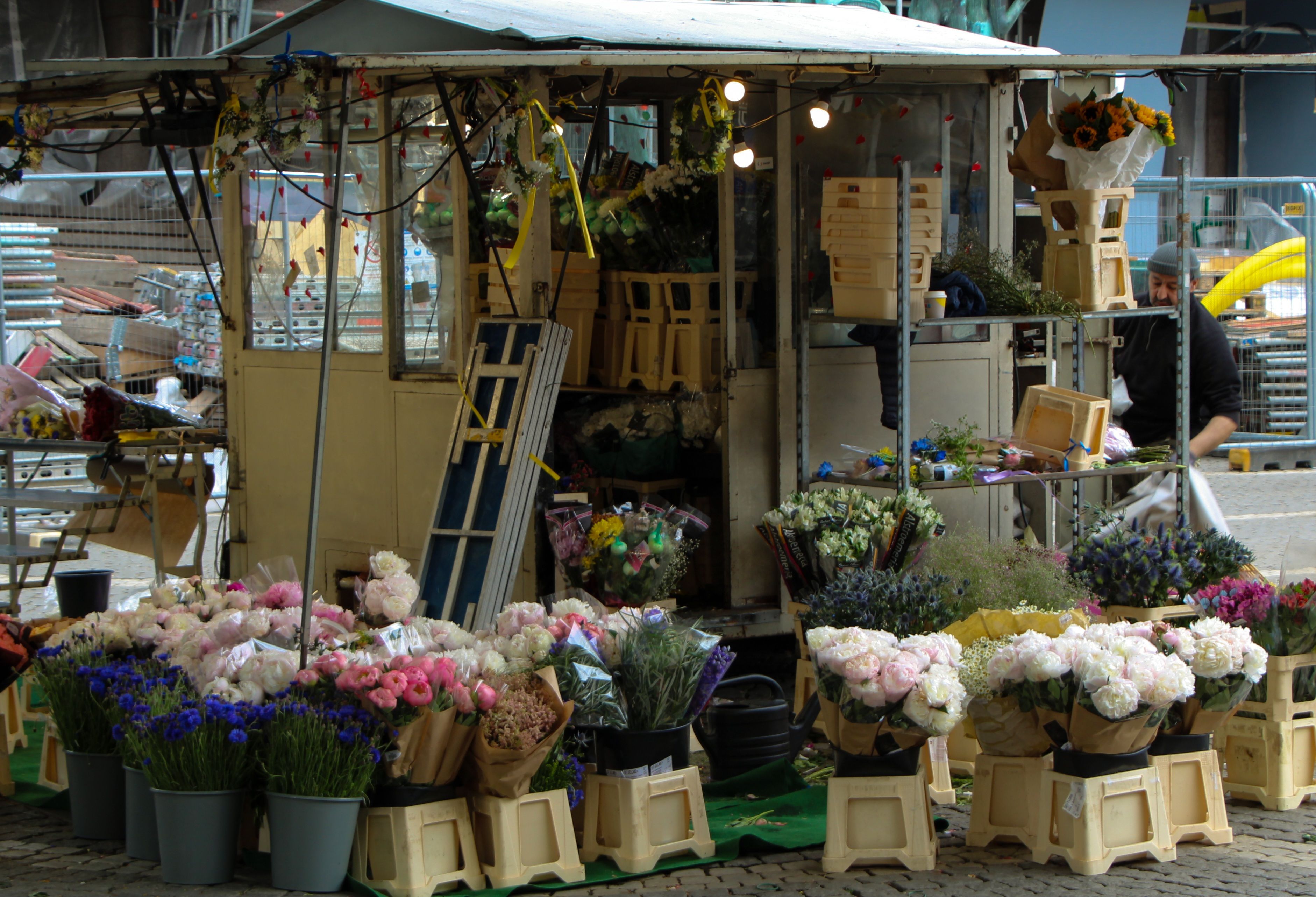 Gratis En indbydende udendørs blomsterbod med farverige buketter og diverse blomster på en travl markedsgade. Lagerfoto