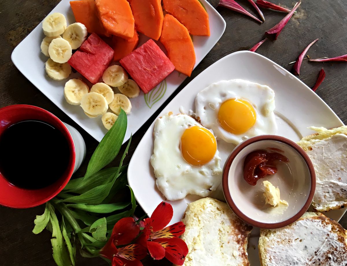 Mesa de café da manhã com prato de ovos, frutas frescas e café para começar o dia com energia