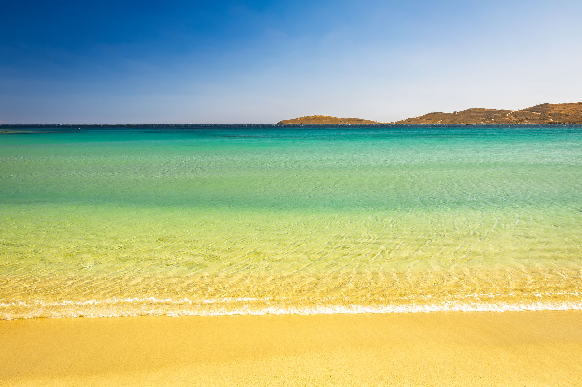 Enjoy a serene view of a sandy beach with crystal clear waters in Greece.