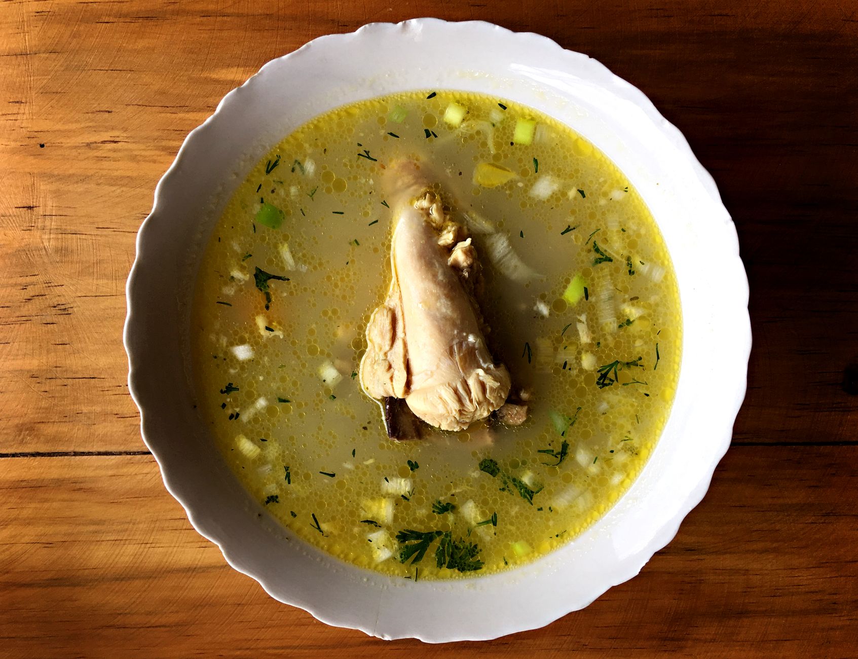 Homemade chicken soup with herbs and matzo balls in a white bowl