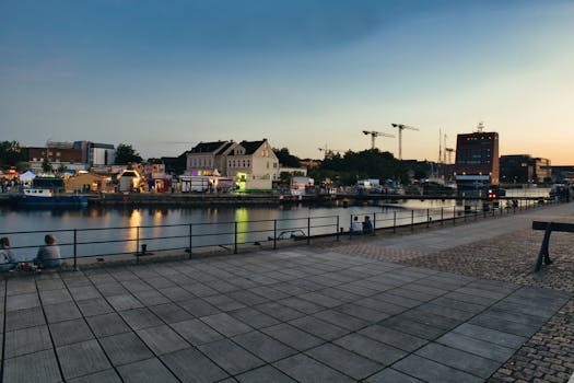 Picturesque harbor scene at dusk with buildings and city lights reflecting on the water.