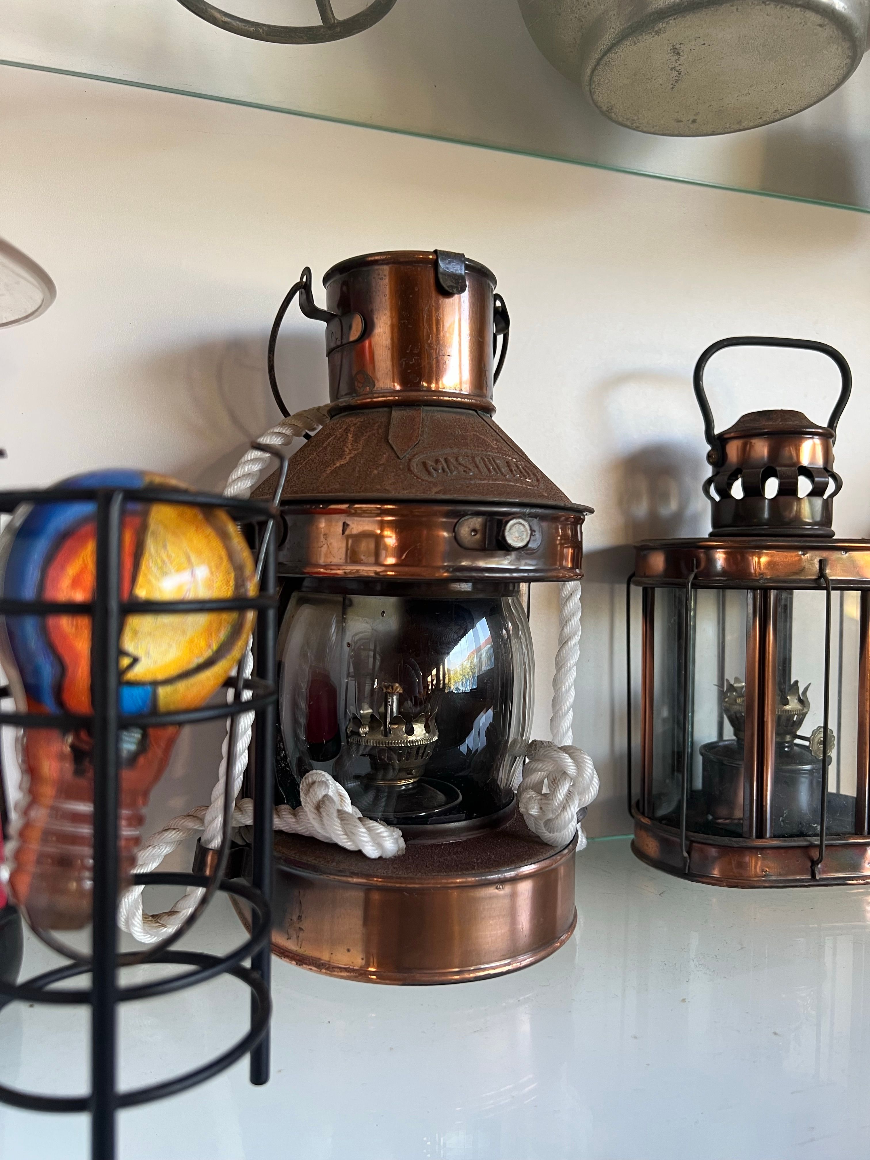 A group of copper and metal nautical lanterns arranged on a shelf, showcasing vintage maritime charm.
