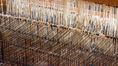 Detailed view of a weaving loom with alpaca wool threads in an artisanal setting.
