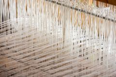 Detailed view of white threads woven on a loom, showcasing intricate textile work.