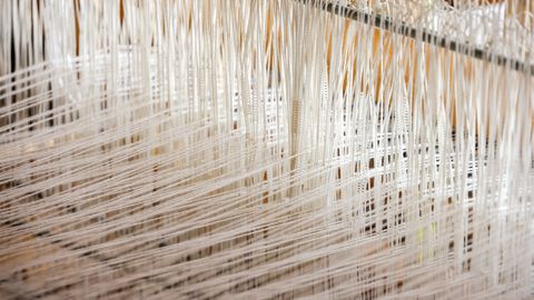 Detailed view of white threads woven on a loom, showcasing intricate textile work.