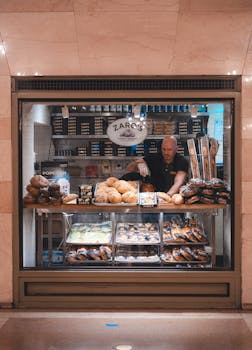 A bakery display window showcasing fresh bread and pastries with a baker inside at a popular New York City location.