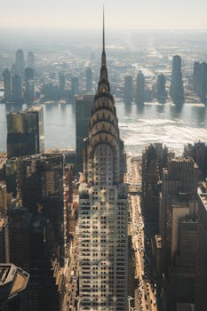 Aerial shot of the Chrysler Building and New York City skyline under a bright day.