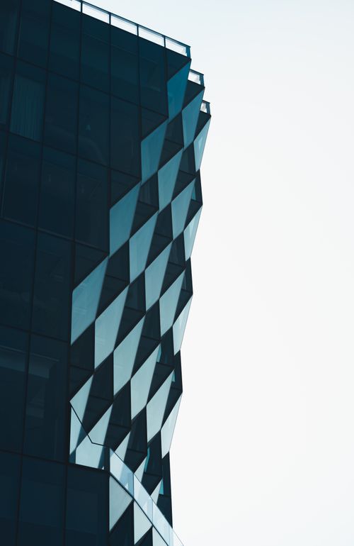 Free Abstract view of modern glass architecture with geometric patterns against a clear sky. Stock Photo
