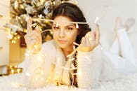 一名女子躺在地毯上，手持圣诞灯，营造出节日而舒适的室内氛围