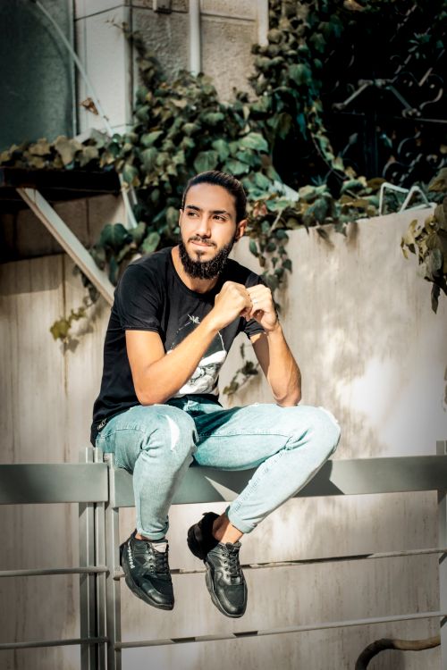 Free Stylish young man sitting on railing outdoors in Syria. Stock Photo
