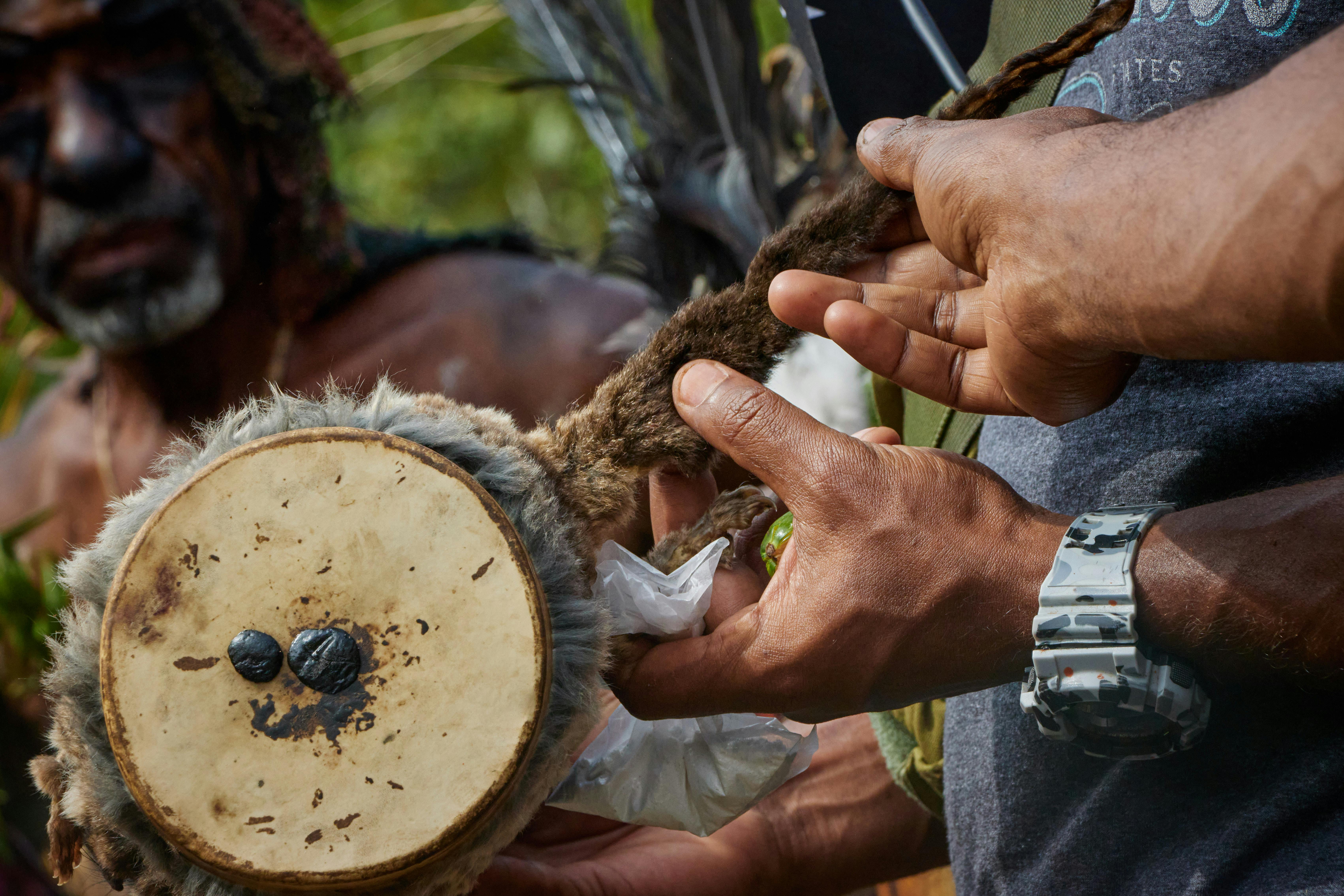Close-up of hands crafting a traditional drum during a cultural ceremony in Papua New Guinea.