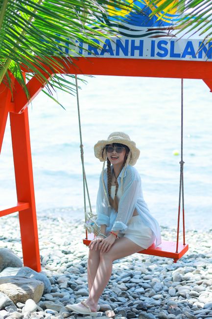 A woman in a sunhat relaxes on a swing by the beach on Phu Quoc Island, enjoying the sunny weather.