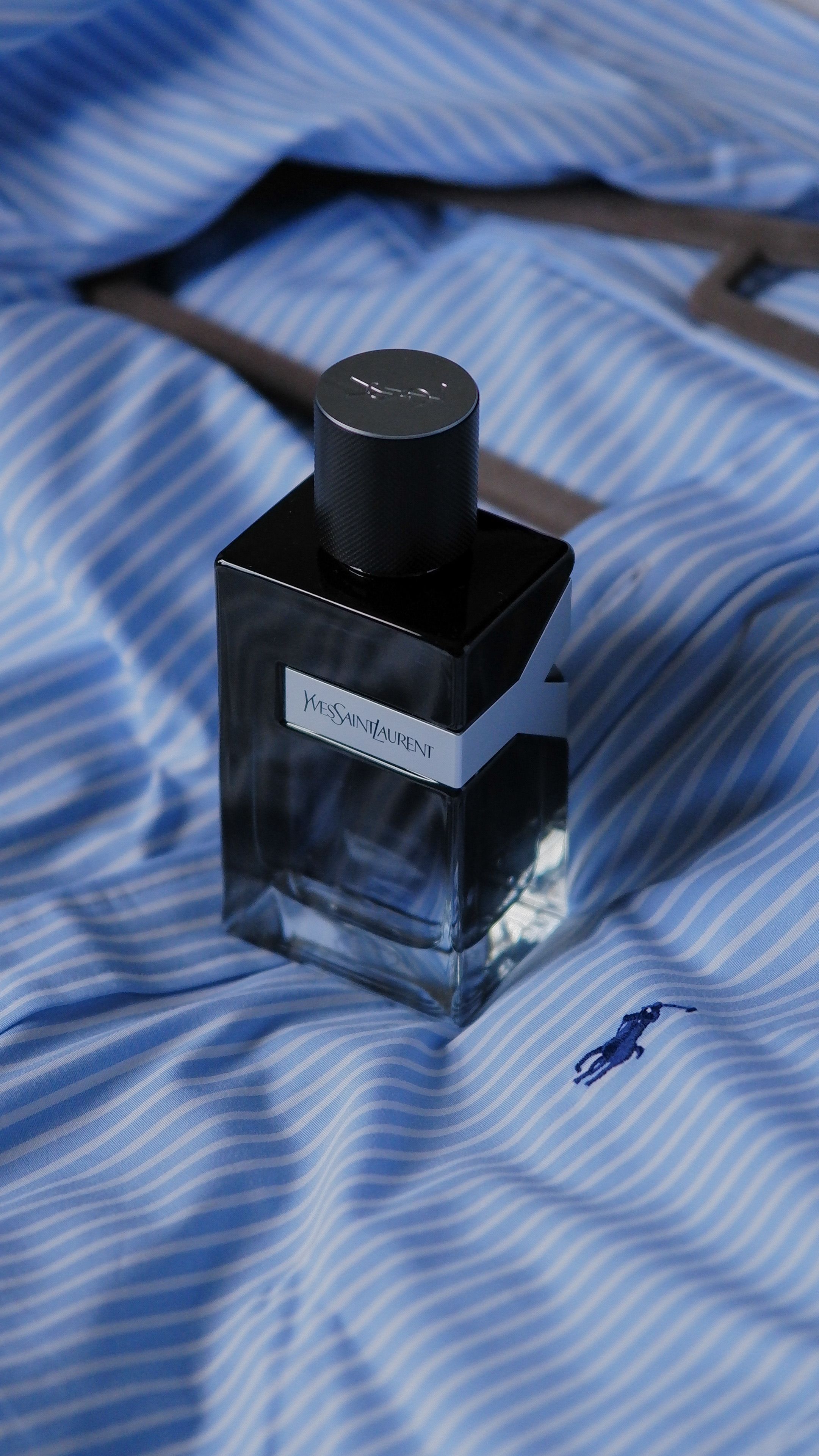 Stylish perfume bottle positioned on luxurious striped blue fabric, evoking sophistication.