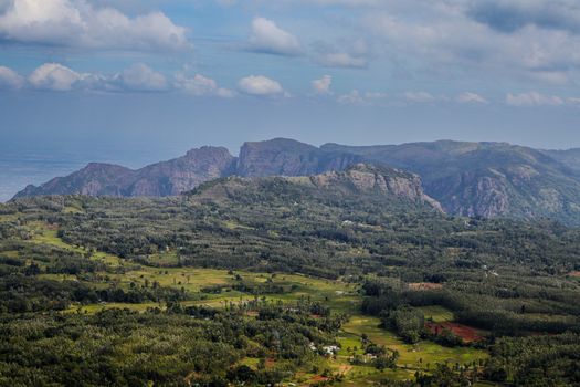 A breathtaking aerial view of lush green valleys and rugged hills under a blue sky in Tamil Nadu, India.