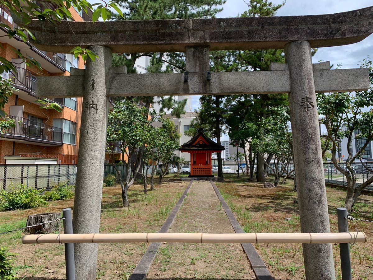 建物に囲まれた境内と石の鳥居