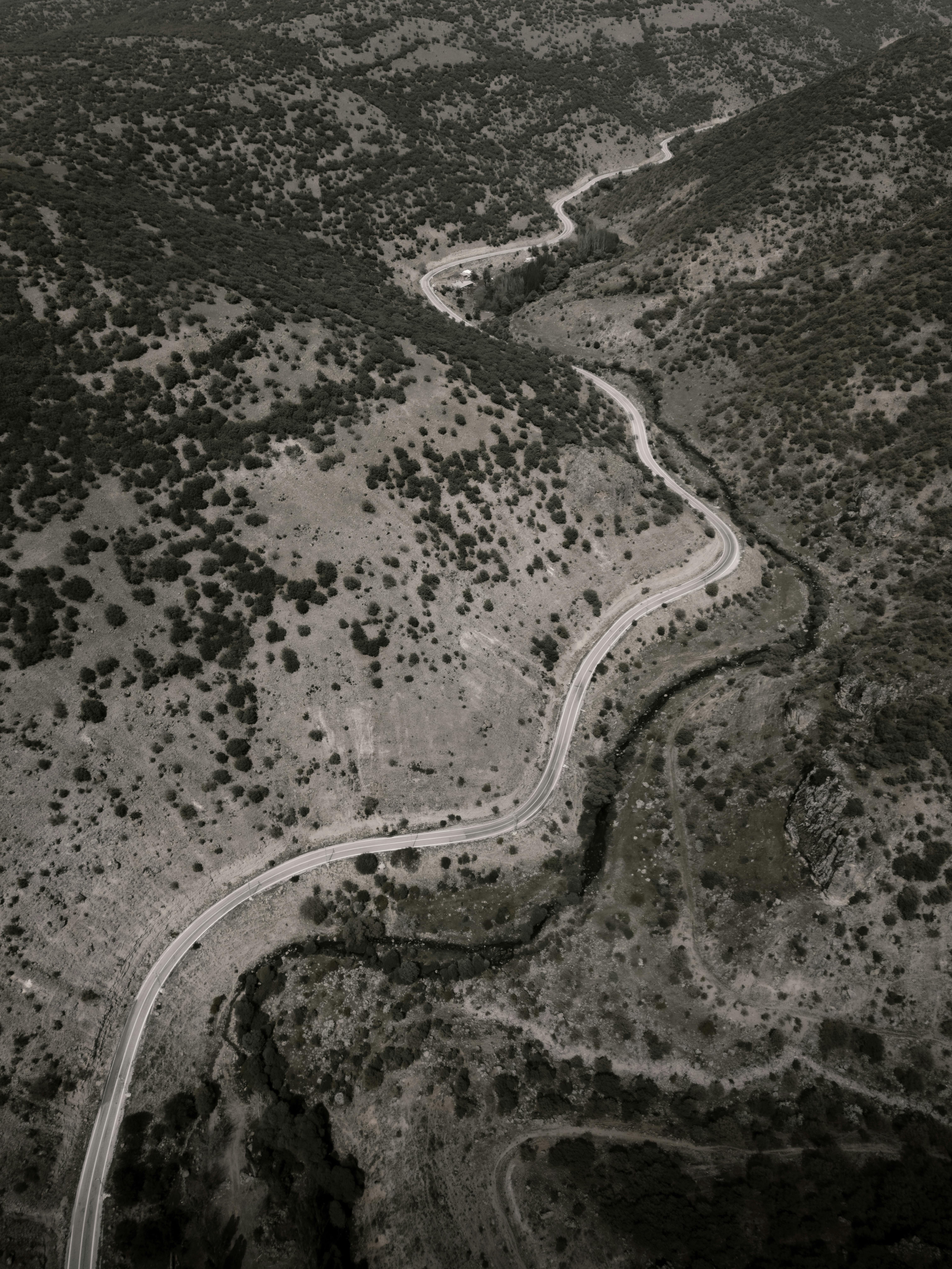 Explore the scenic aerial view of a winding mountain road through rugged terrain.