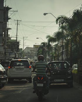 Traffic scene in Dimapur, India showcasing cars and motorbike on a busy street.