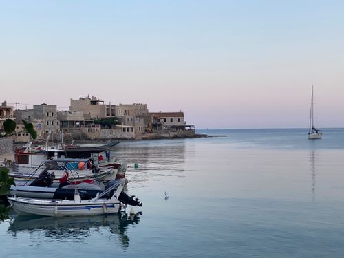 Free Peaceful evening scene at Limeni, Greece with boats and historic stone buildings by the sea. Stock Photo