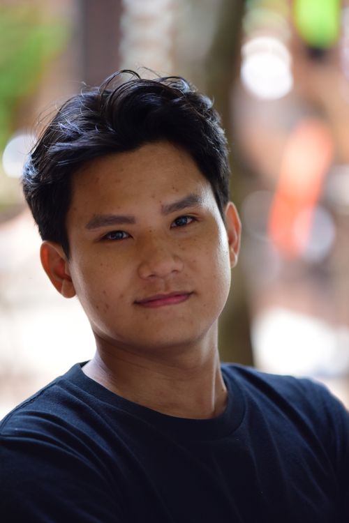 Free A close-up portrait of a young adult smiling, captured outdoors in natural light. Stock Photo