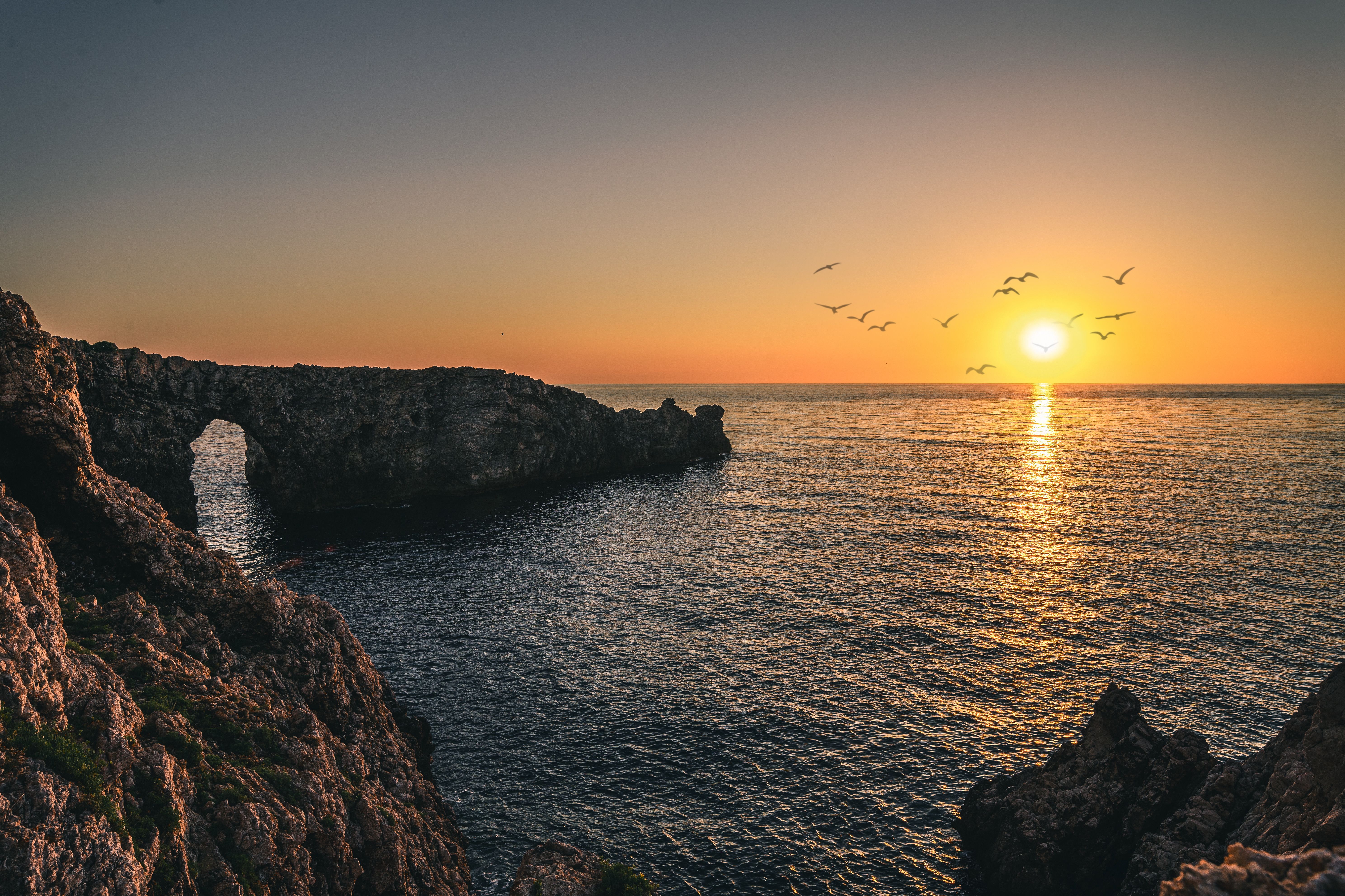 Dramatic Coastal Sunset with Arch and Birds · Free Stock Photo